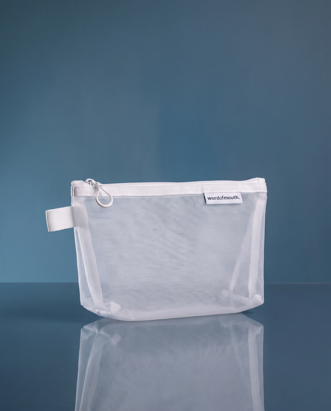 Word of Mouth Essentials Case, a fine white mesh zip pouch with a webbing loop and woven wordofmouth label