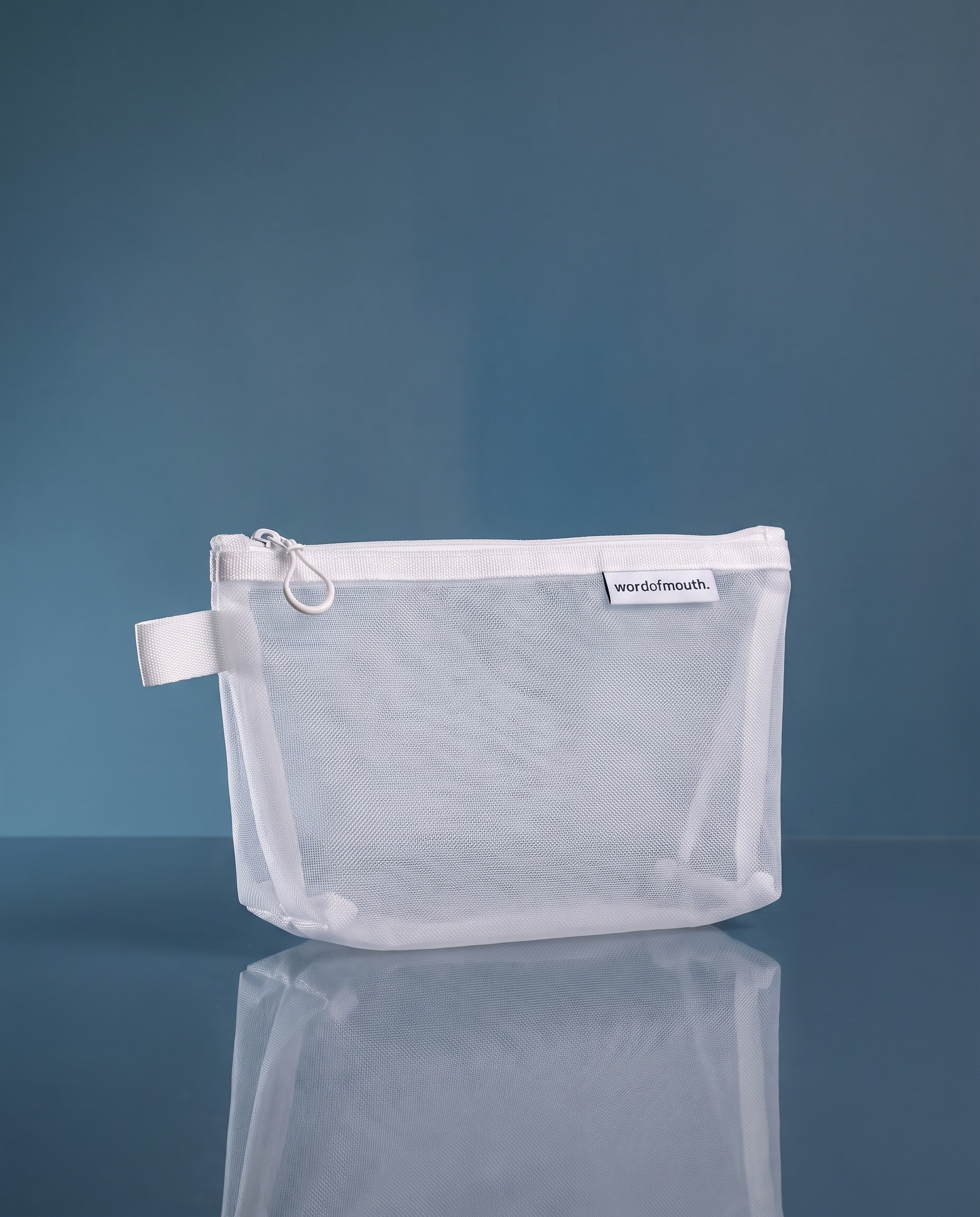 Word of Mouth Essentials Case, a fine white mesh zip pouch with a webbing loop and woven wordofmouth label