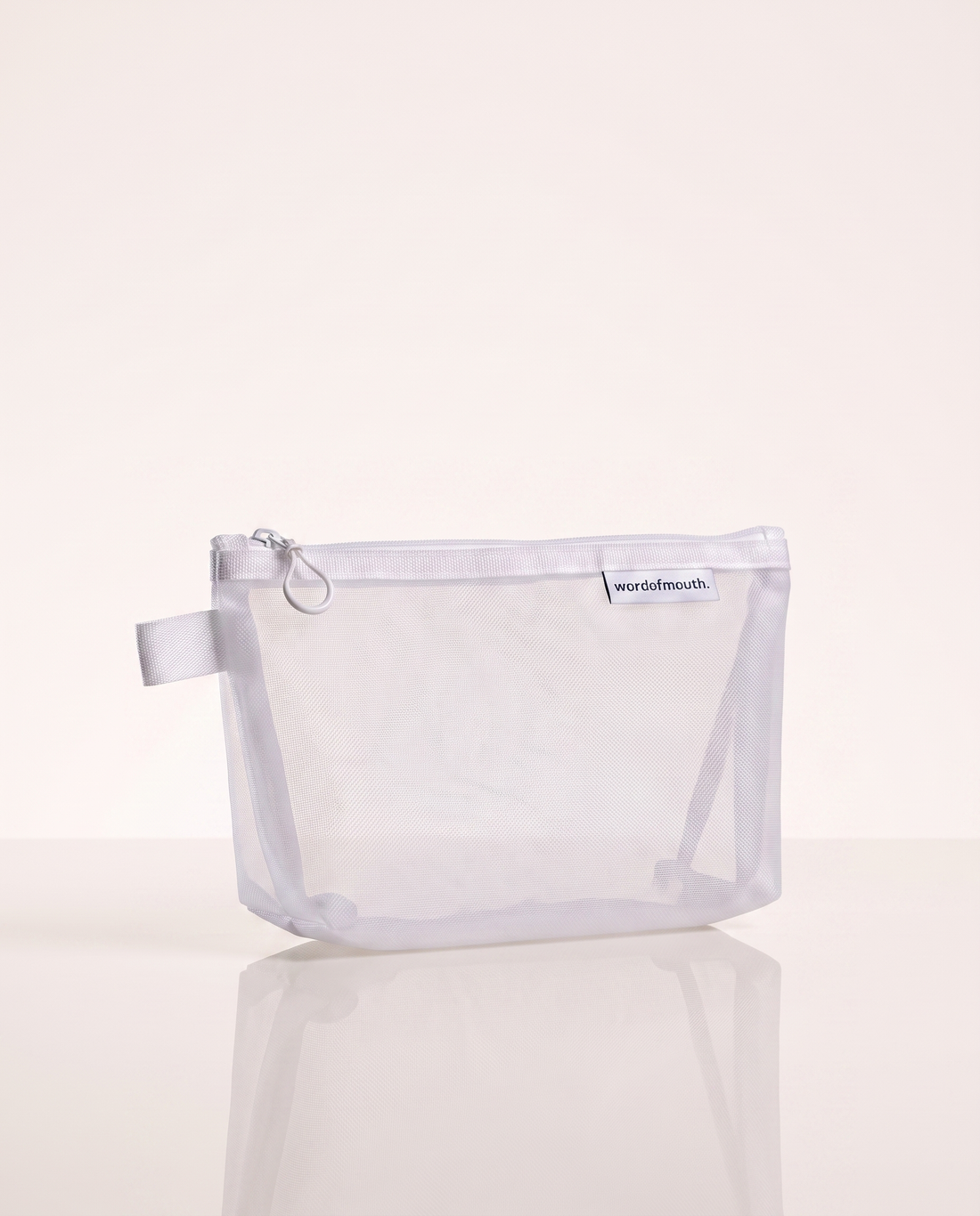 Essentials Case mesh travel pouch on a warm white reflective surface